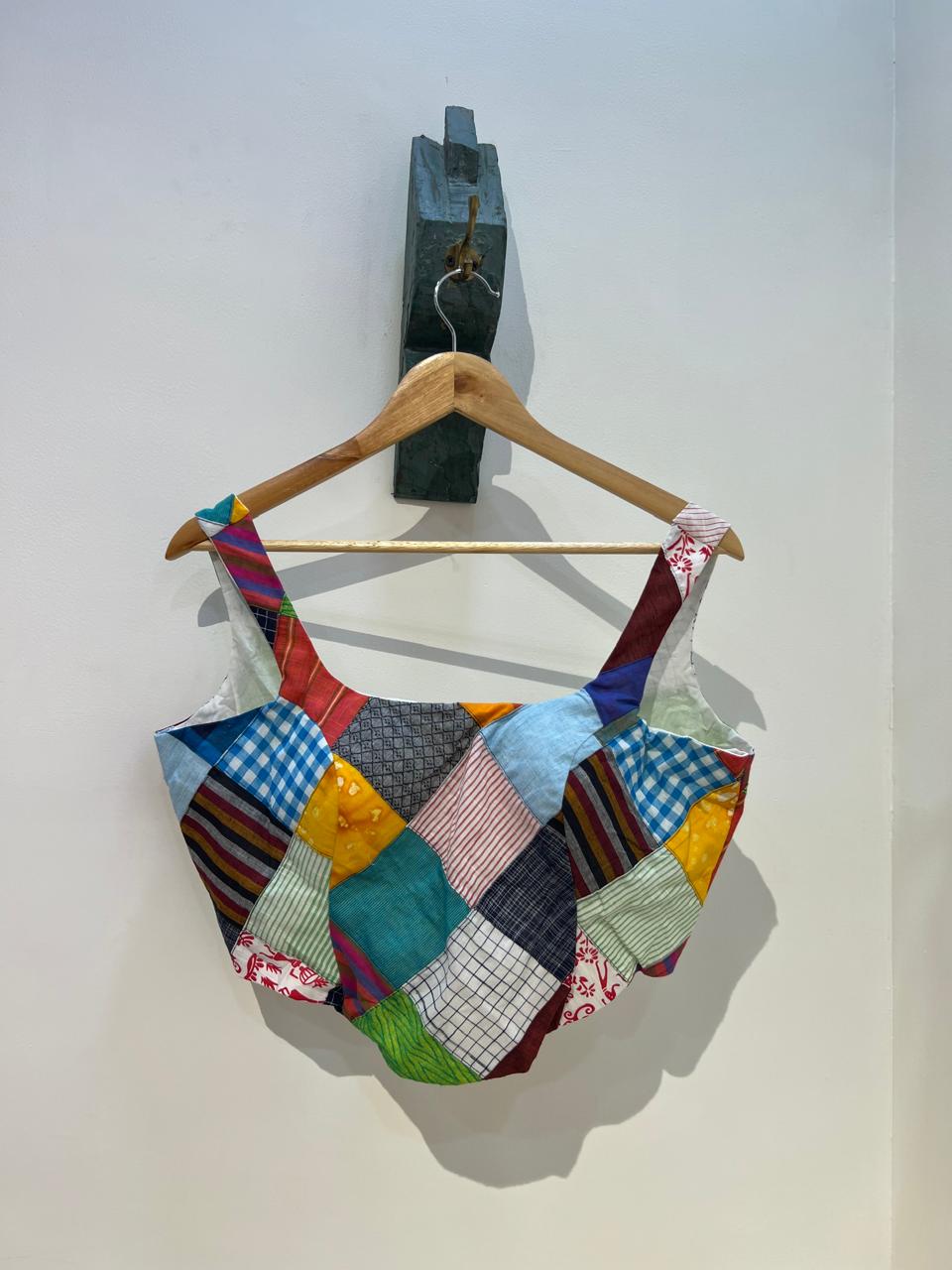 Colorful patchwork blouse
 on a wooden hanger against a white background